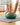 Close-up of hands pressing a green Trideer mini exercise ball on a yoga mat.
