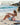 Woman doing mat Pilates on a beach with a pink mini exercise ball supporting her lower back