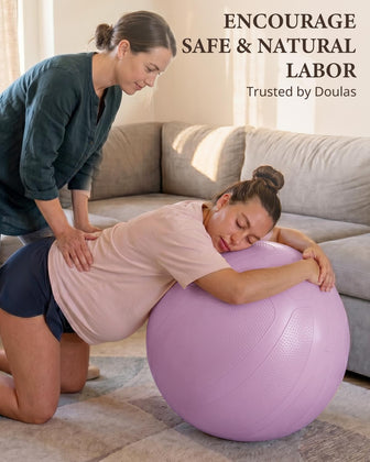 Pregnant woman kneeling and leaning over a purple birthing ball with support from another woman.